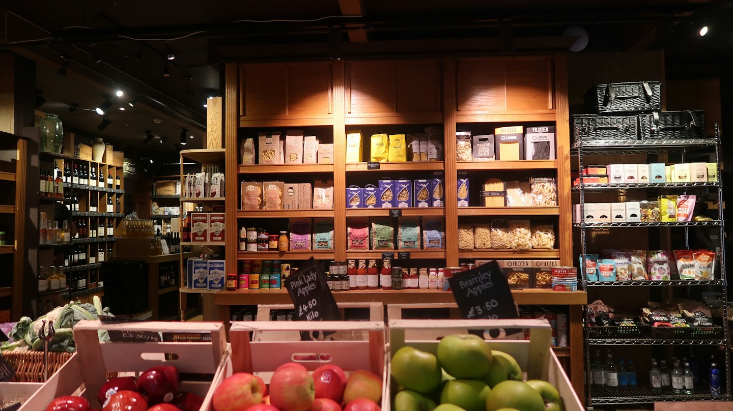Wooden crates of apples sit in a well stocked grocery store.